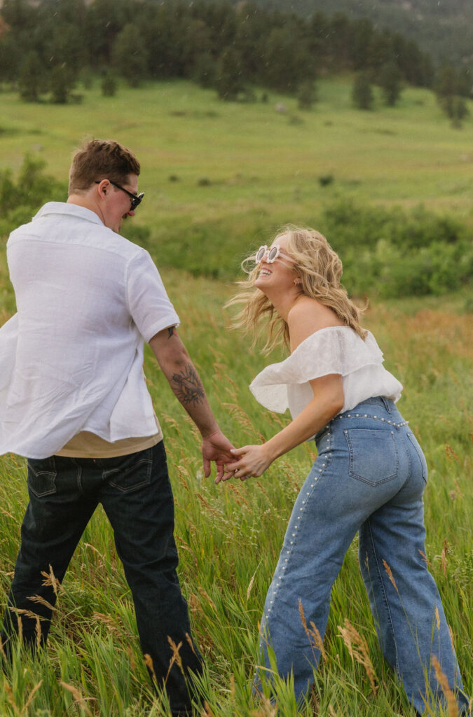 Candid laughter as couple embraces the post-rain magic during their wildflower engagement session