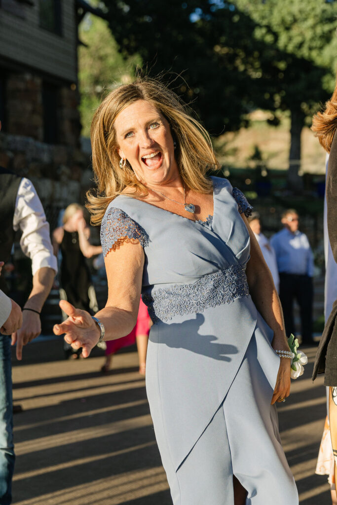 Joyful wedding guest in silver dress dancing at outdoor Colorado wedding reception