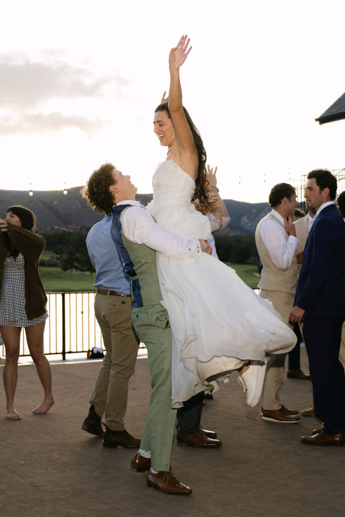 Bride being lifted in the air by wedding party during celebration at Colorado Front Range wedding