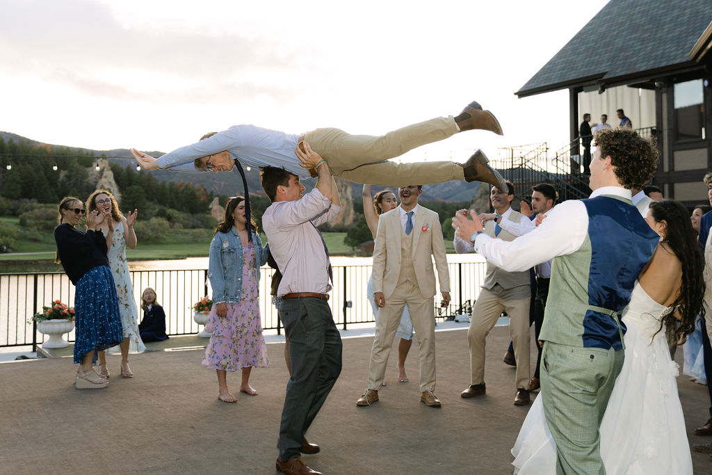Wedding guest being lifted up at Colorado wedding reception with mountain landscape backdrop