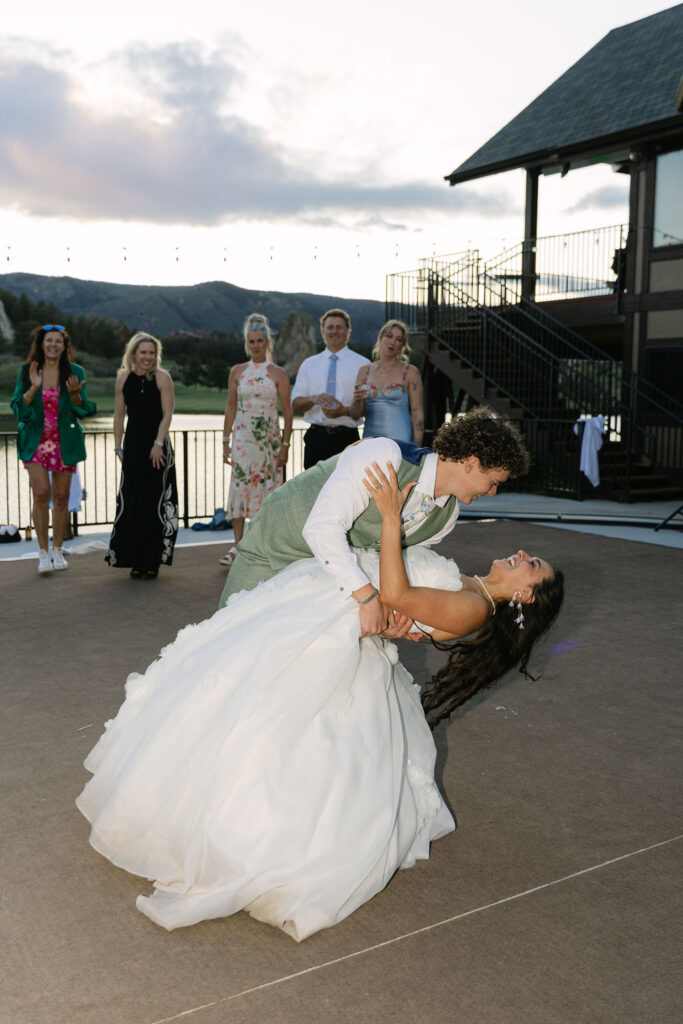 Bride and groom dipping dance move on covered patio at Colorado lakefront wedding with mountain views