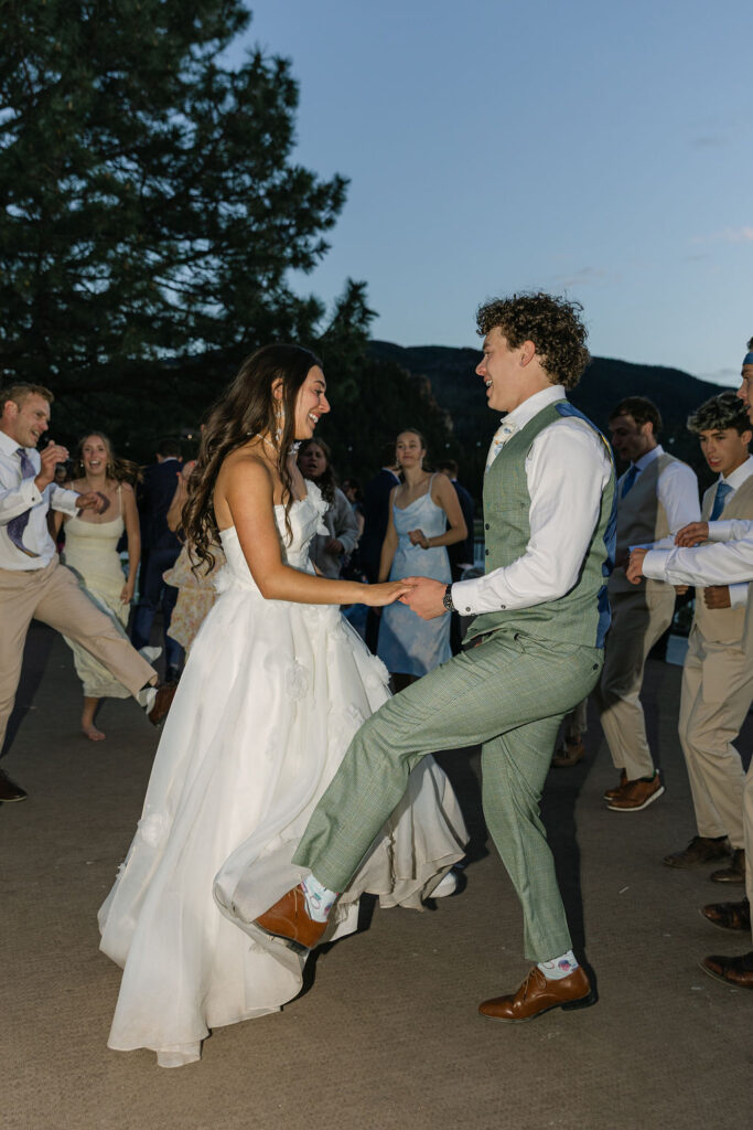 Flash reception photo of bride and groom dancing together at outdoor Colorado mountain wedding reception with guests watching