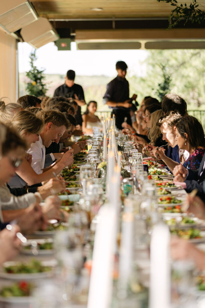 Guests enjoying their salads during an outdoor reception with family style table seating