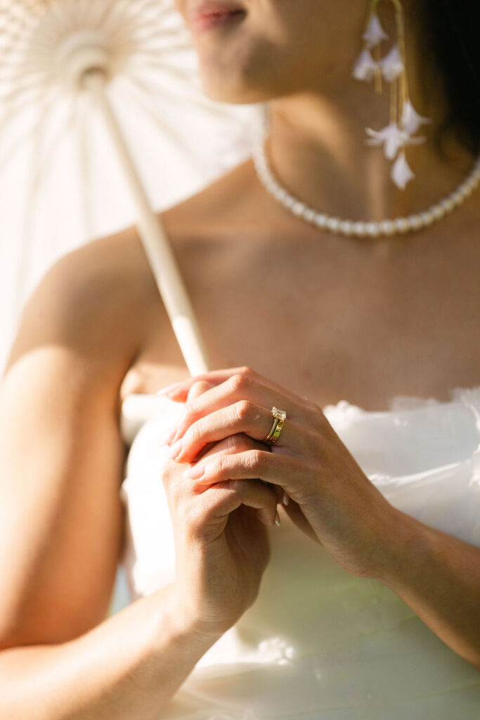 Romantic bridal detail photo of ring while holding parasol at golden hour