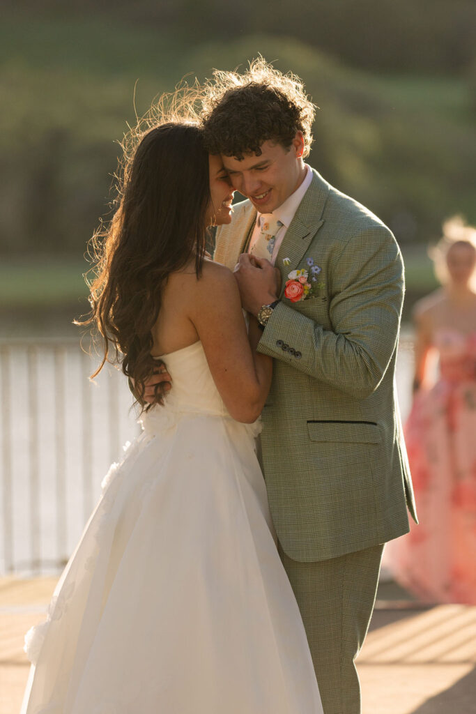 Romantic bride and groom first dance at sunset during Perry Park Country Club lakefront wedding with soft lighting