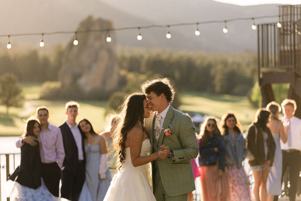First dance at golden hour Colorado mountain wedding with string lights and golf course views at lakefront venue