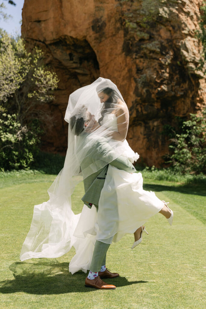 Romantic bride and groom portrait with flowing wedding dress and veil against the scenic red rocks