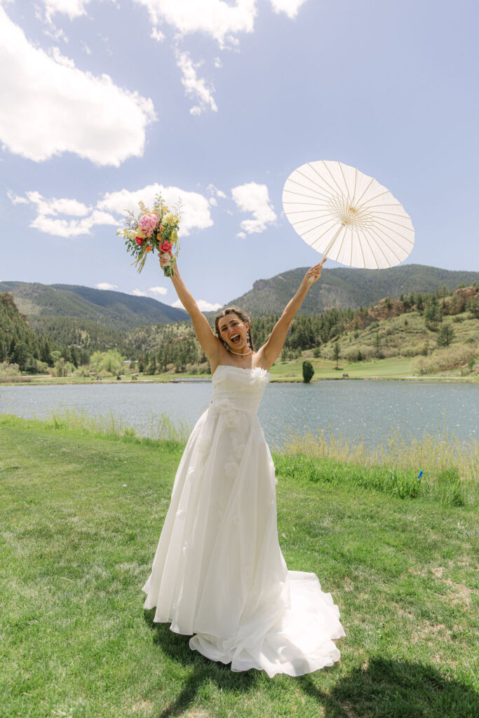 Bride with white parasol celebrating with mountain views at Perry Park Country Club wedding