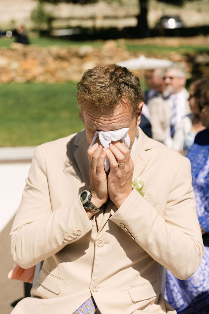 Emotional father of the groom reaction during Perry Park Country Club wedding ceremony with guests in background