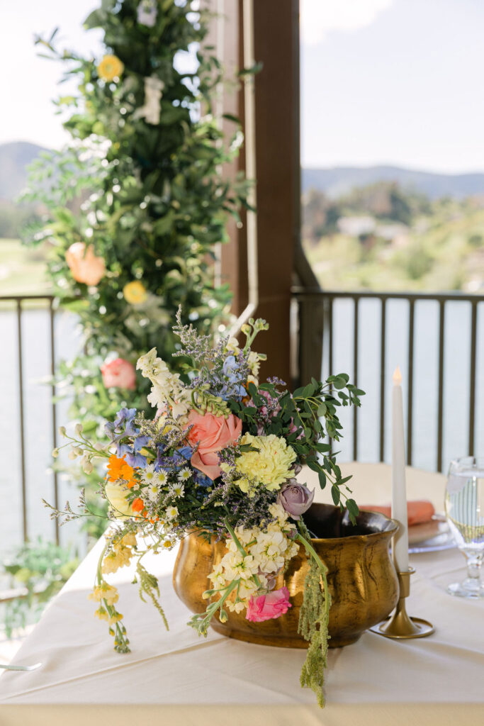 Colorful garden-style wedding centerpiece with wildflowers in brass vessel at Perry Park Country Club reception