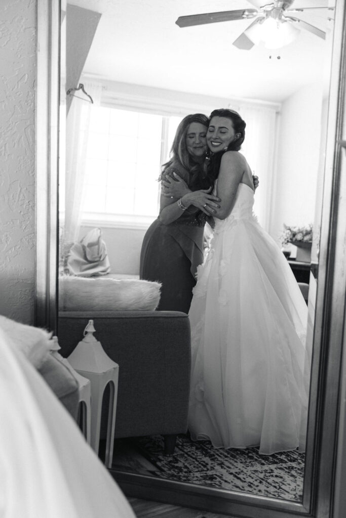 Candid moment of bride and mom getting ready in the mirror in the bridal suite