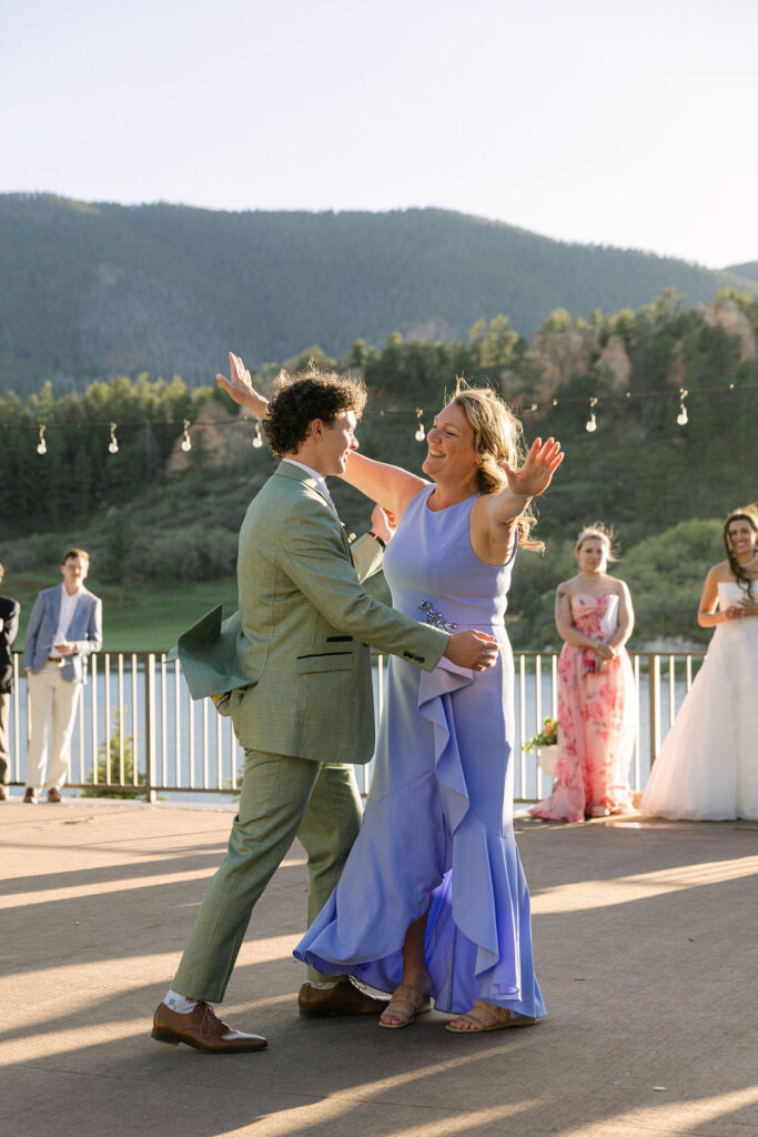 Groom dancing with mother in blue dress at Perry Park Country Club outdoor reception with mountain views