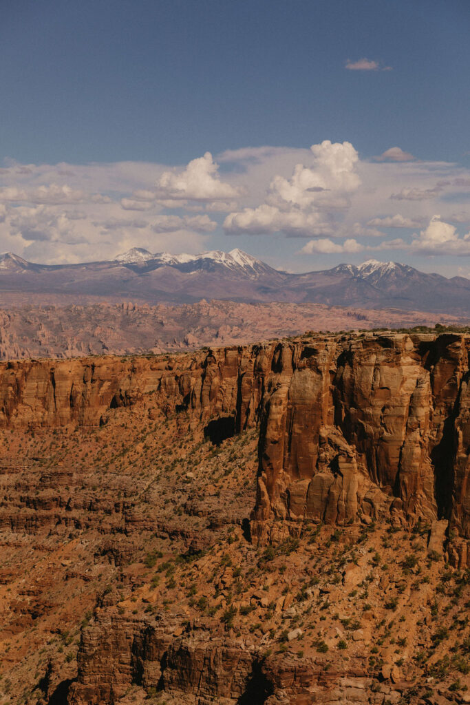 High cliff edge in Canyonlands with jagged rock walls and the La Sal Mountains in the distance, showcasing the dramatic scenery that surrounds Moab’s best outdoor wedding venues.