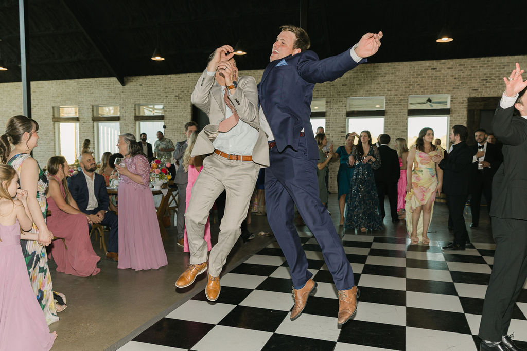 Two guests leap into the air during a lively dance circle at this Texas wedding reception.