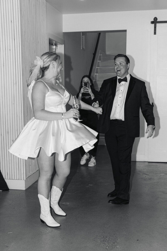 The bride twirls in her short dress and cowgirl boots, mid-dance with the groom on the reception dance floor.