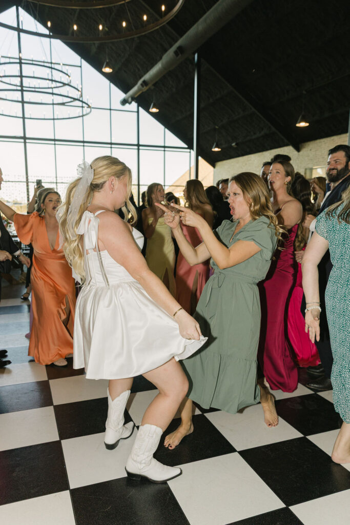 A high-energy photo of the bride mid-dance with one of her guests, capturing the vibrant energy of this Houston-area wedding.