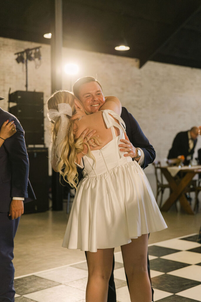 The bride embraces the groom tightly, smiling through happy tears during their Camp Hosea reception.