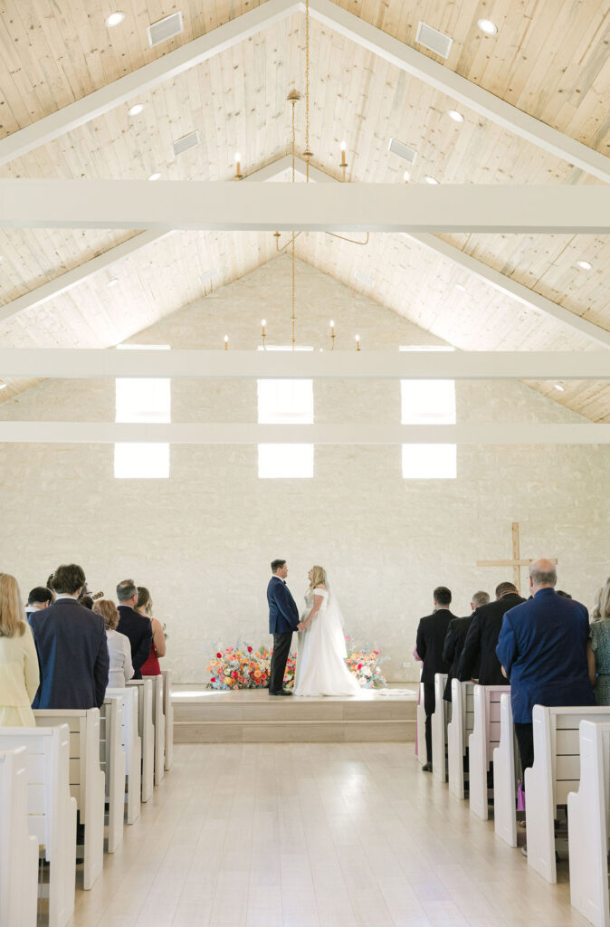 A bride and groom exchange vows inside Camp Hosea’s bright, whitewashed chapel, filled with natural light and modern architecture.