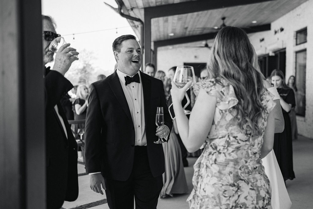 A candid of the groom sharing a heartfelt moment and toast with a guest during cocktail hour at this Houston wedding venue.