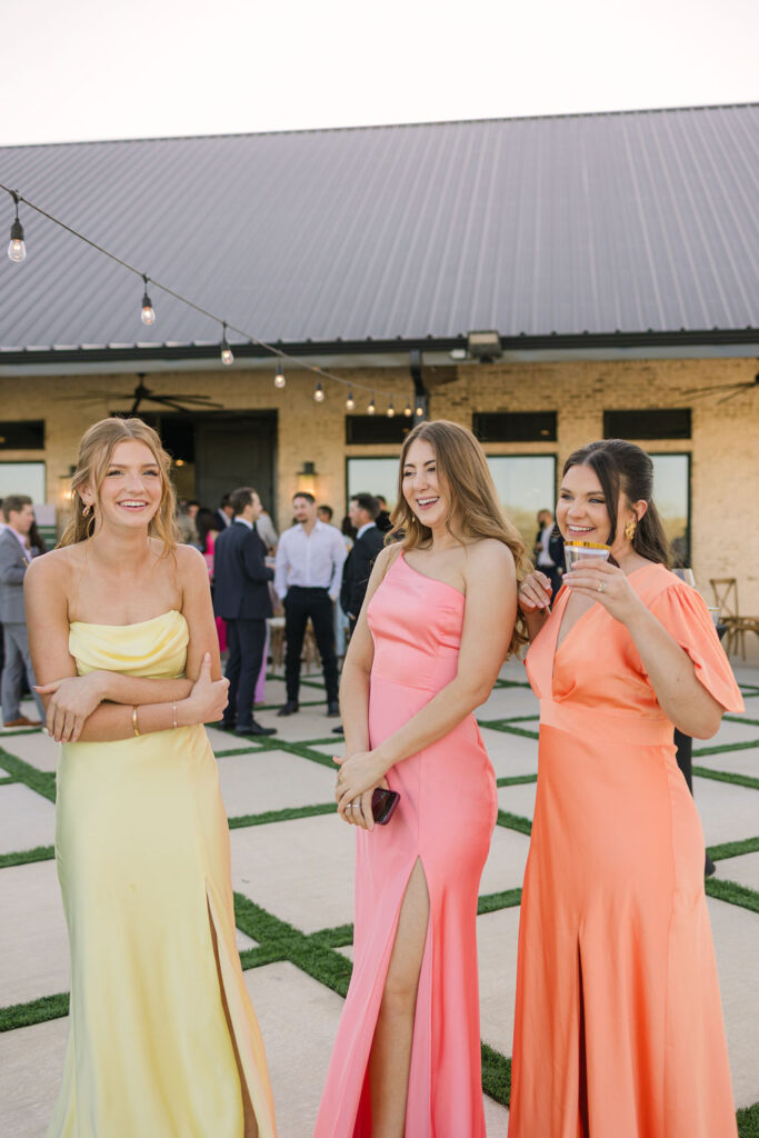 A group of bridesmaids walk the lawn, their gowns flowing in shades of lemon, peach, and rose—perfect for spring weddings in Texas.