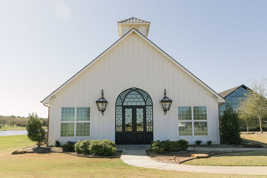 A clean white chapel with dramatic black doors at Camp Hosea wedding venue in Anderson, Texas, perfect for elegant and modern Texas weddings.