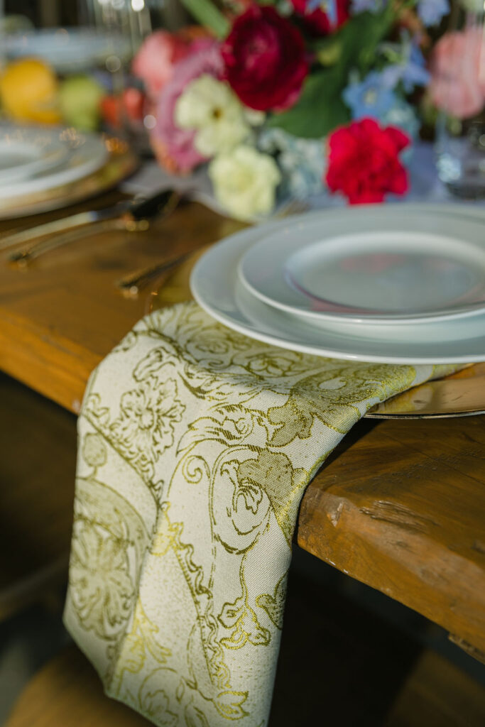 A soft gold and sage damask table runner decorates rustic wooden tables for this elegant Houston wedding reception.