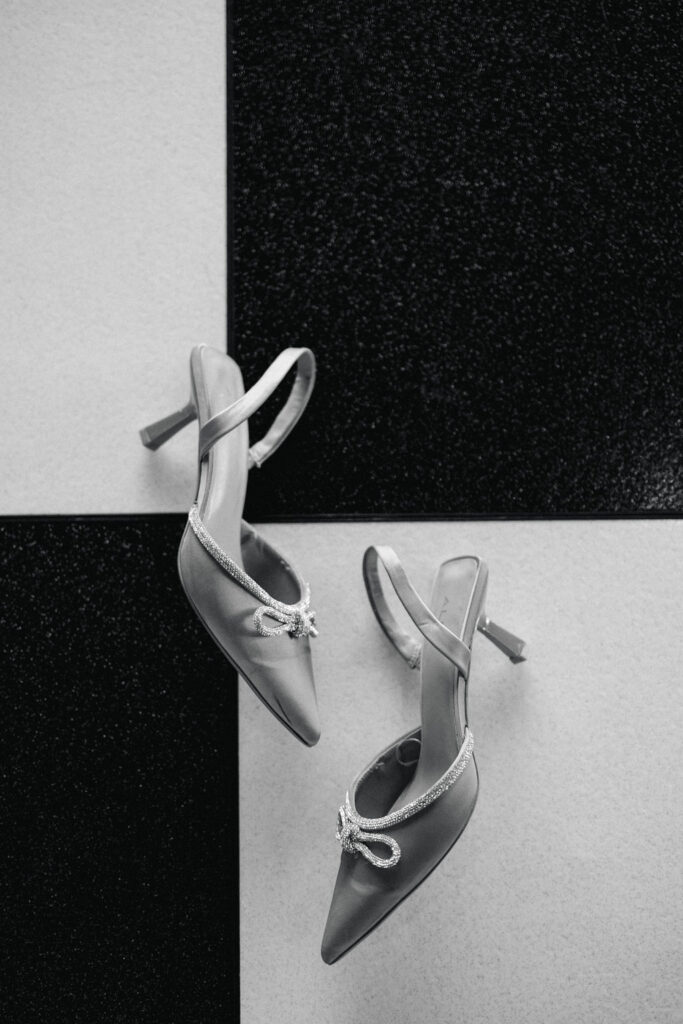 A minimalist black-and-white image of the bride’s heels styled on the checkered floor, evoking modern wedding day elegance in Texas.