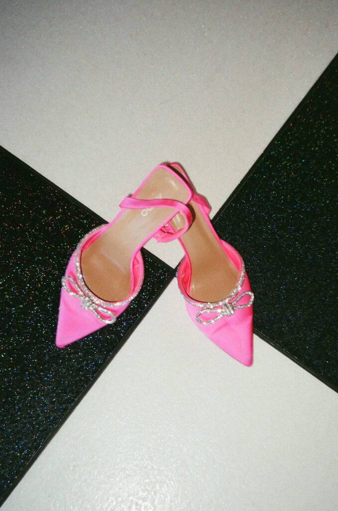 Bright pink bridal shoes placed on the venue’s checkered floor—adding fun, modern flair to this Camp Hosea wedding day.