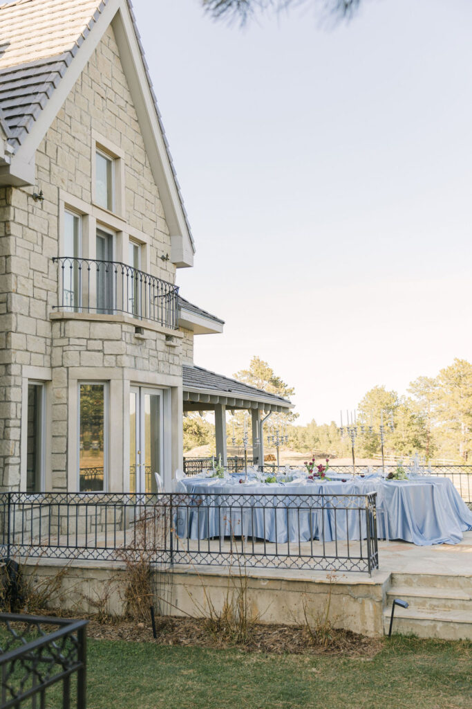 Outdoor wedding reception space set up at Greystone Castle adorned with elegant florals, and tall silver candelabras, all set against the elegant stone exterior.