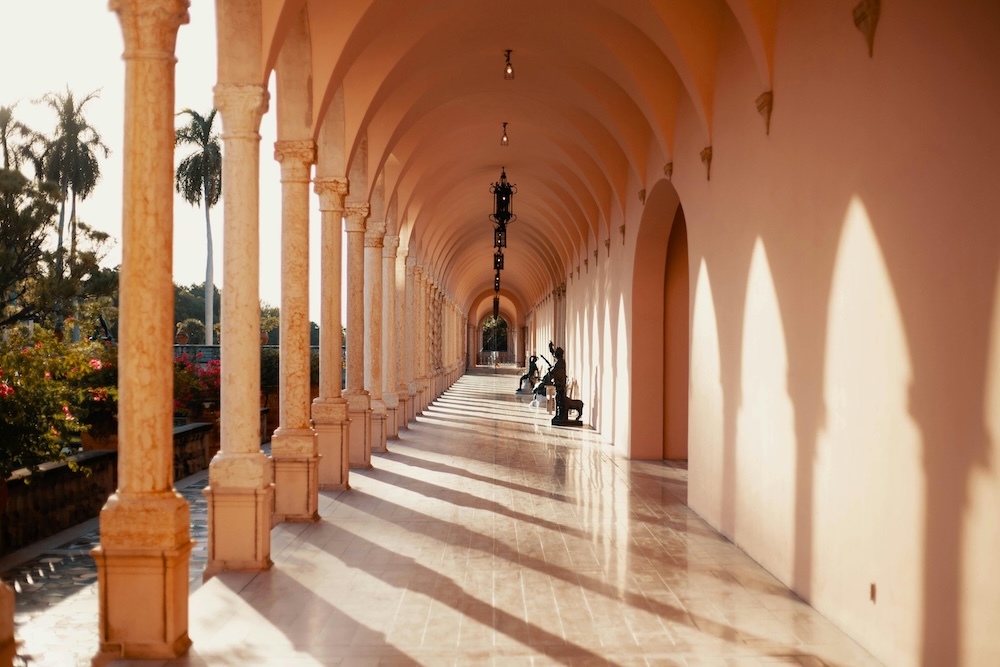 Golden hour light floods the arched pink hallway of the Ringling Museum in Sarasota, Florida—an elegant, European-inspired wedding venue with timeless architectural charm and dreamy photo backdrops.