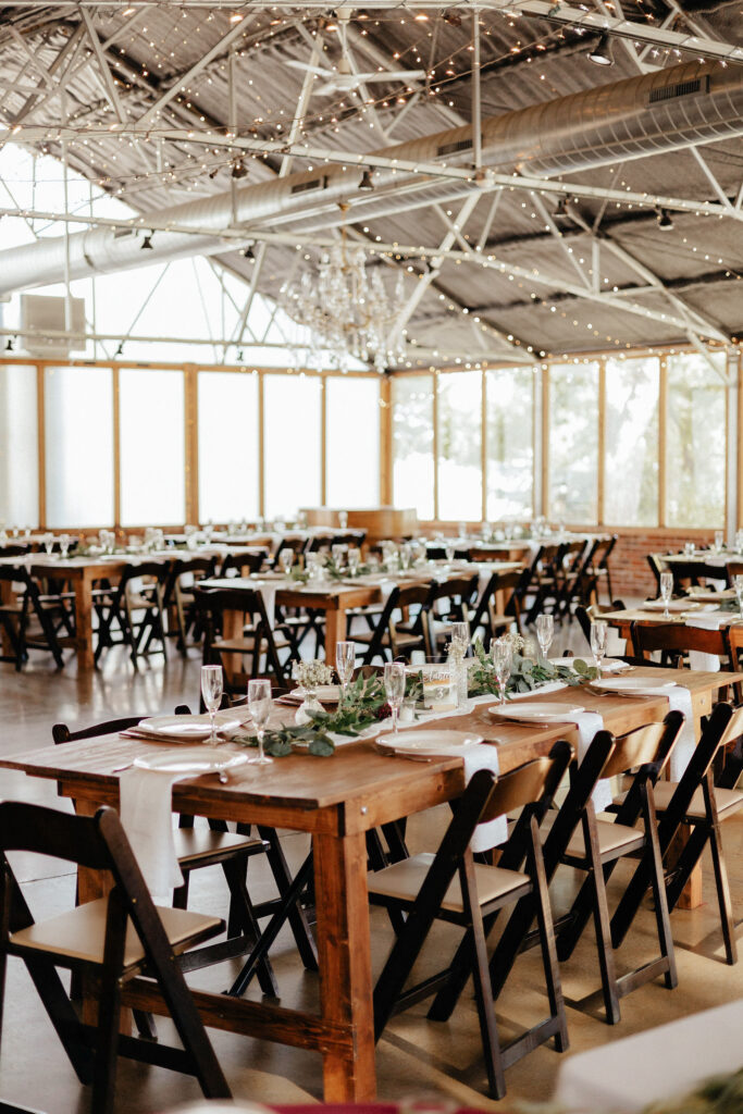 Indoor reception space inspiration with natural light and gorgeous wooden tables adorned in eucalyptus