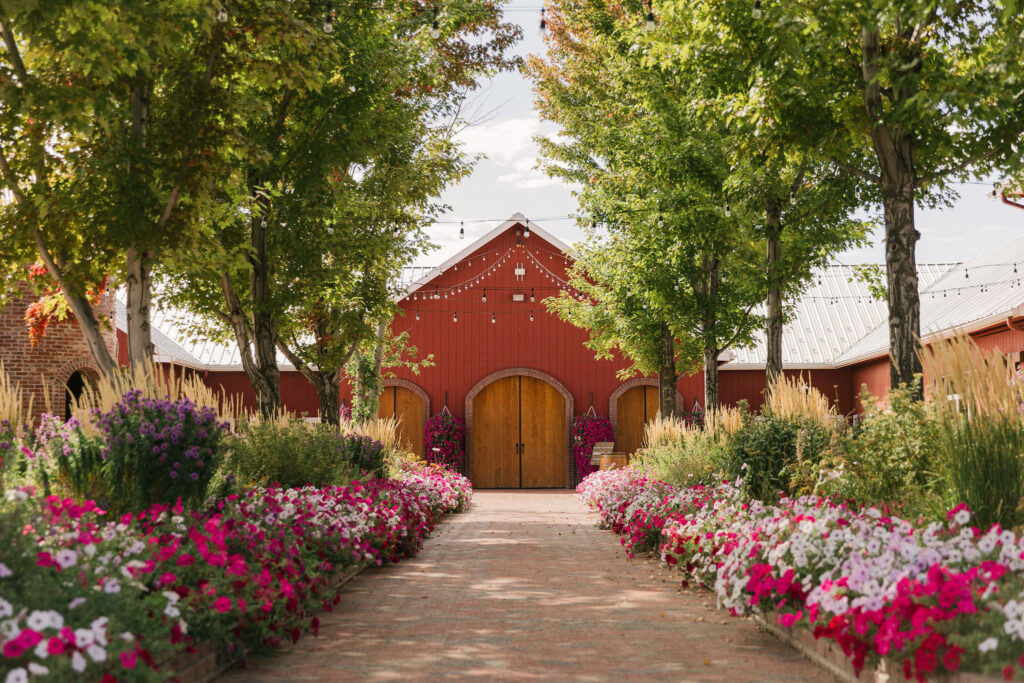 the lush garden and red barn style building at The Venue at Crooked Willow Farms