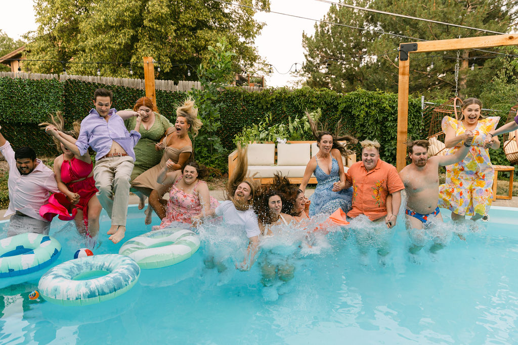 wedding couple and guests jumping in the pool together