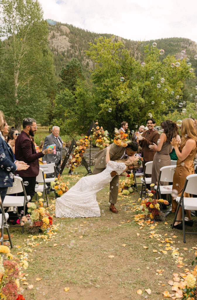 bride and groom dip kiss after their small wedding ceremony at venue on the rocks