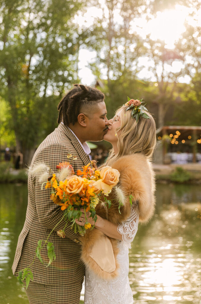 happy bride and groom kissing during their wedding day at the venue on the rocks