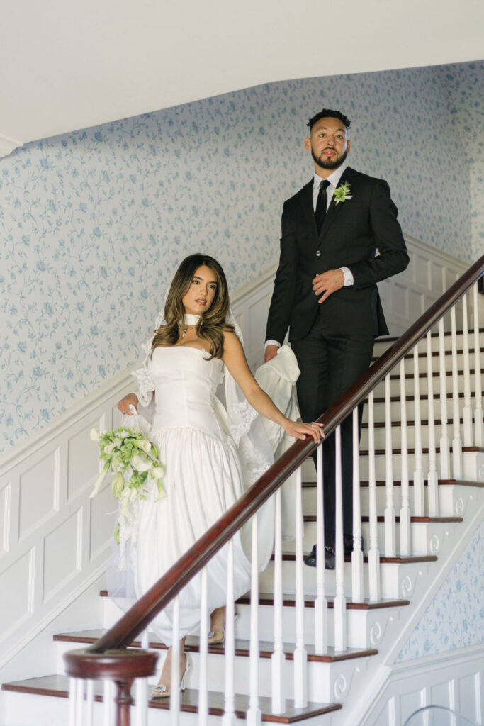 bride and groom walking down the stairs with cute vintage wallpaper in the background