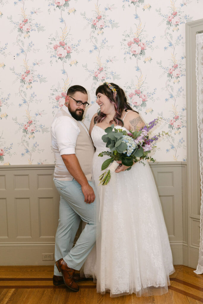 bride and groom indoors in front of a vintage floral wallpaper