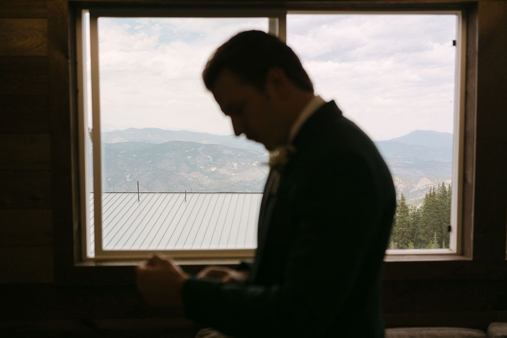 Silhouette of a groom getting ready for his Colorado mountain wedding ceremony 