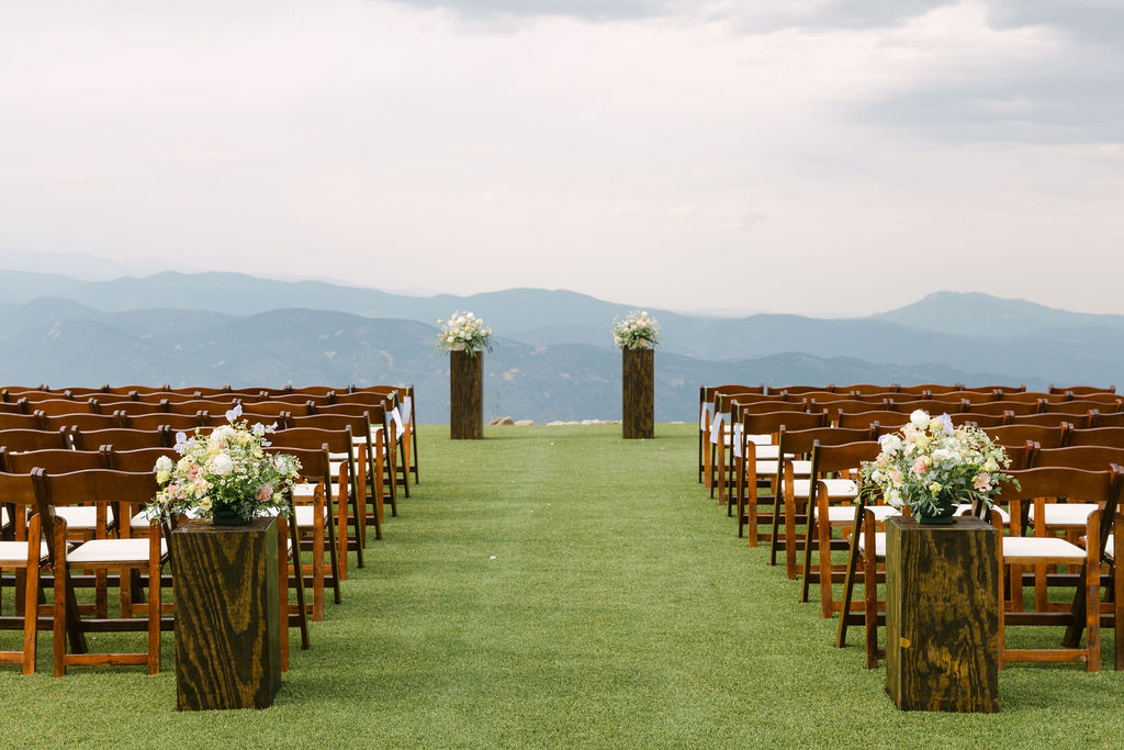 Breathtaking Colorado mountain wedding ceremony aisle with colorful florals placed on wooden pillars