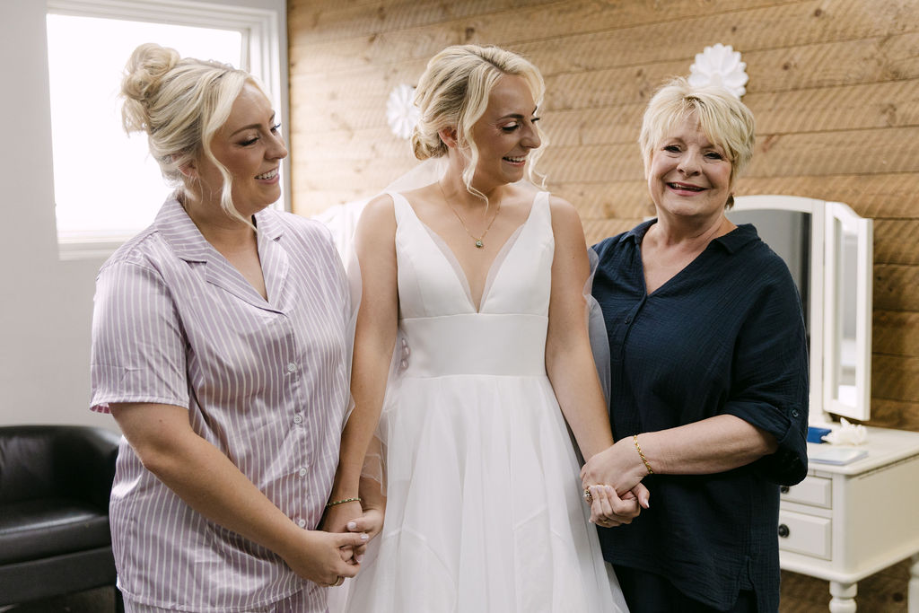 Bride holding hands lovingly with her mom and sister preparing for her first look at Echo Lake 