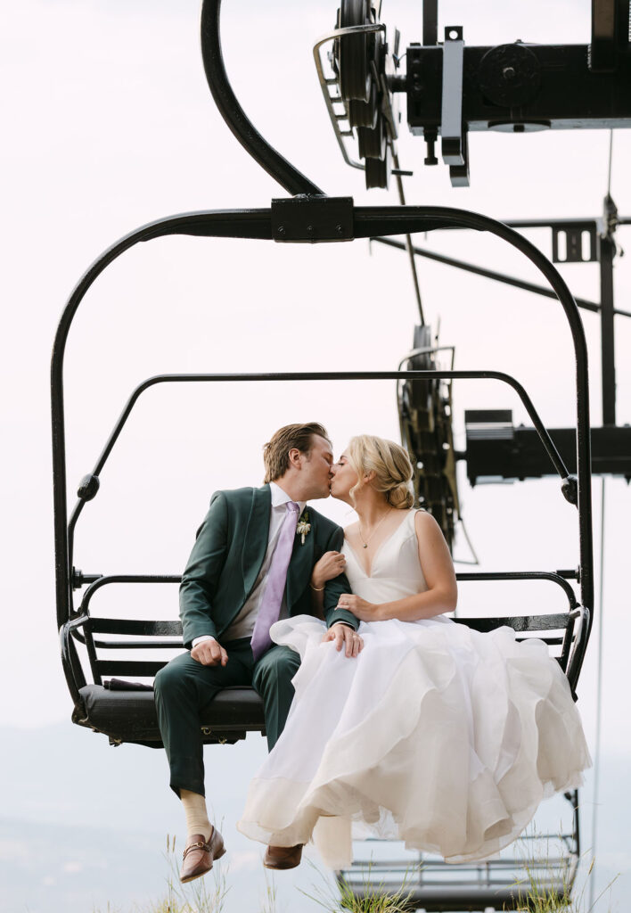 Bride and groom kissing on the ski lift at Echo Mountain after their wedding ceremony