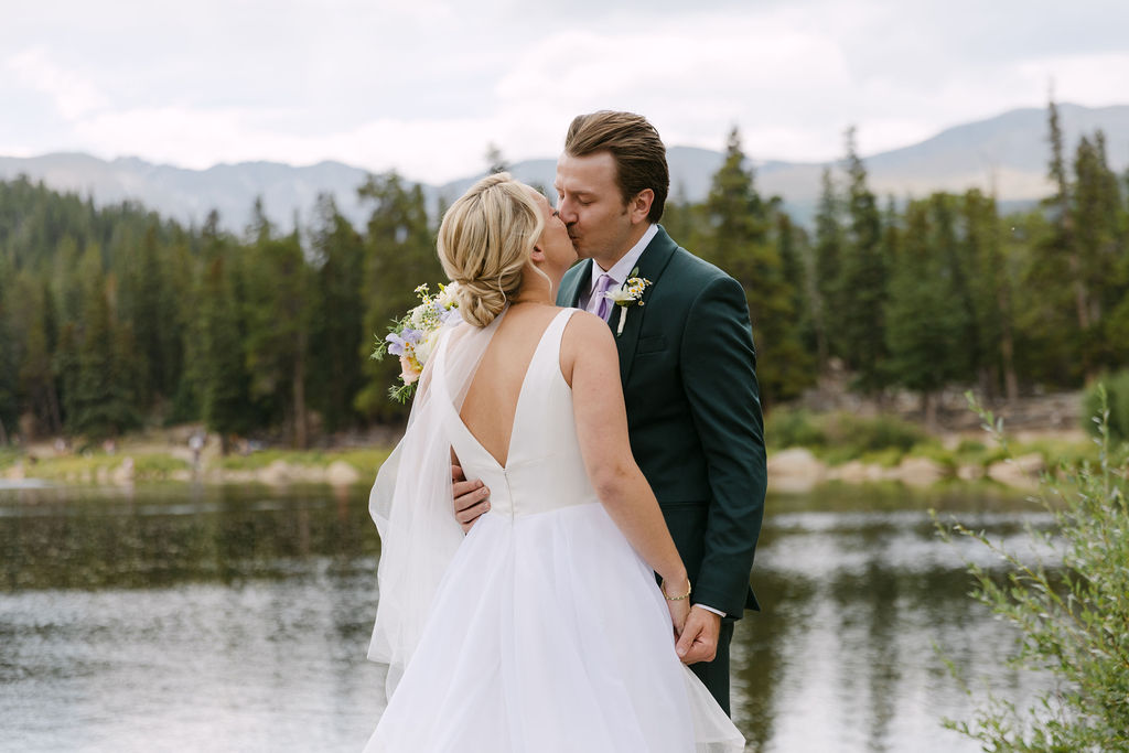 Bride and groom kissing by Echo Lake with a serene mountain backdrop 