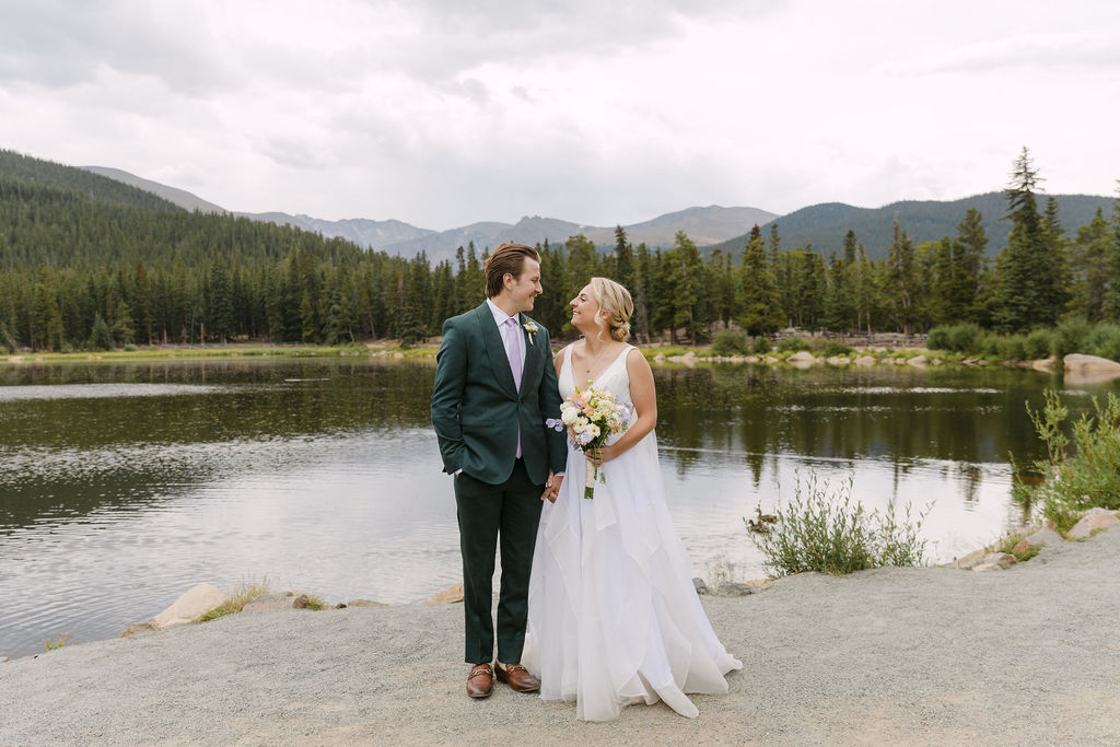 Bride and groom holding hands smiling at each other after their first look at Echo Lake 