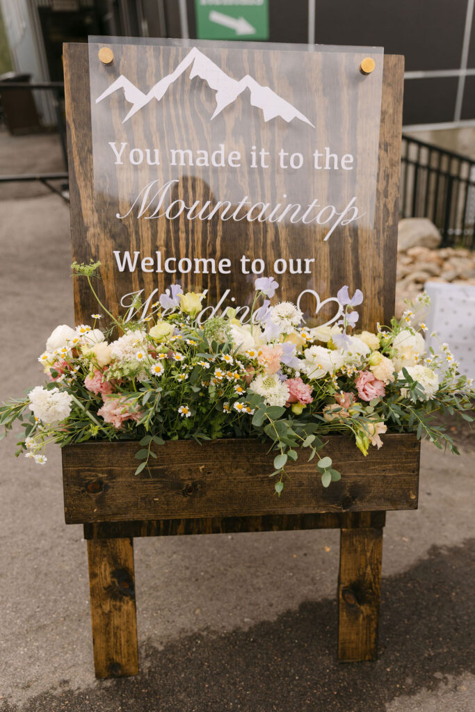 Ski resort wedding signage adorned with colorful florals 
