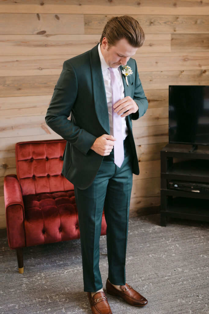 Groom fixing his purple tie in the groom's suite at Echo Mountain preparing for his first look