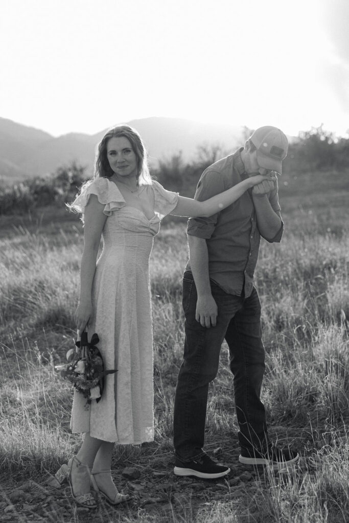 Couple walking hand in hand across a grassy hill at Horsetooth Reservoir.