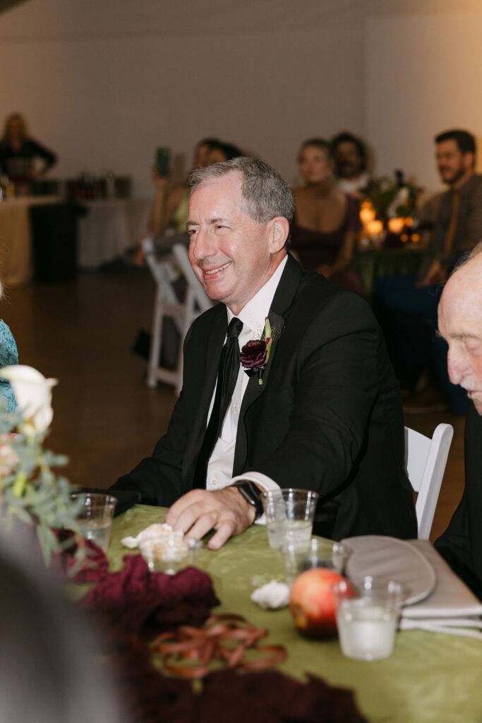 Father of the bride smiling during dinner toasts at an elegant Hudson Gardens wedding reception.