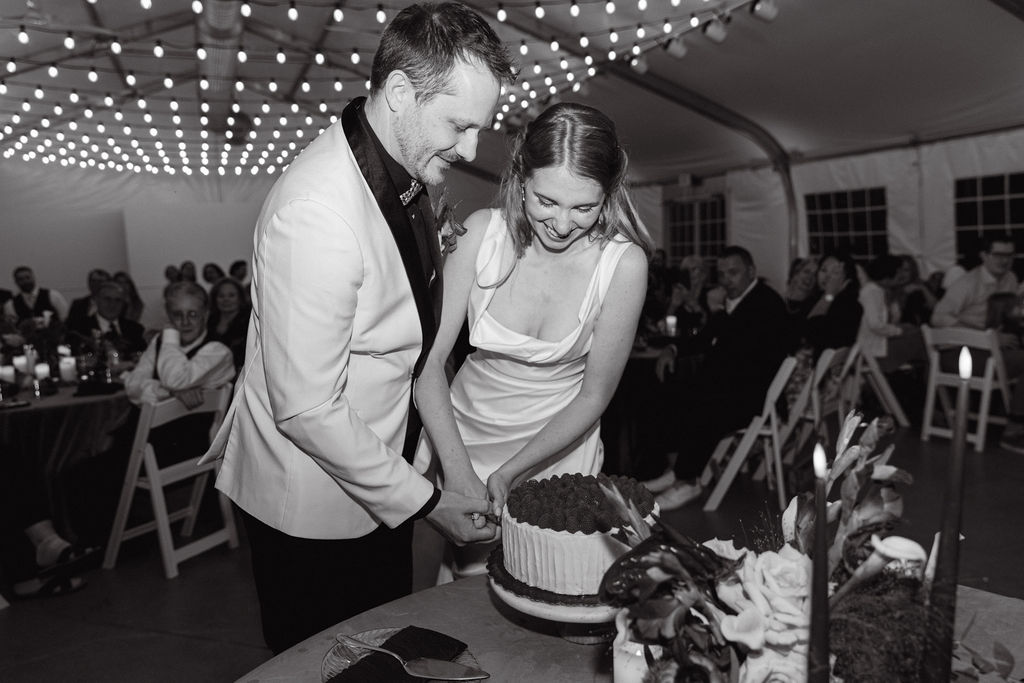 Black-and-white photo of bride and groom cutting the cake at their Hudson Gardens wedding.