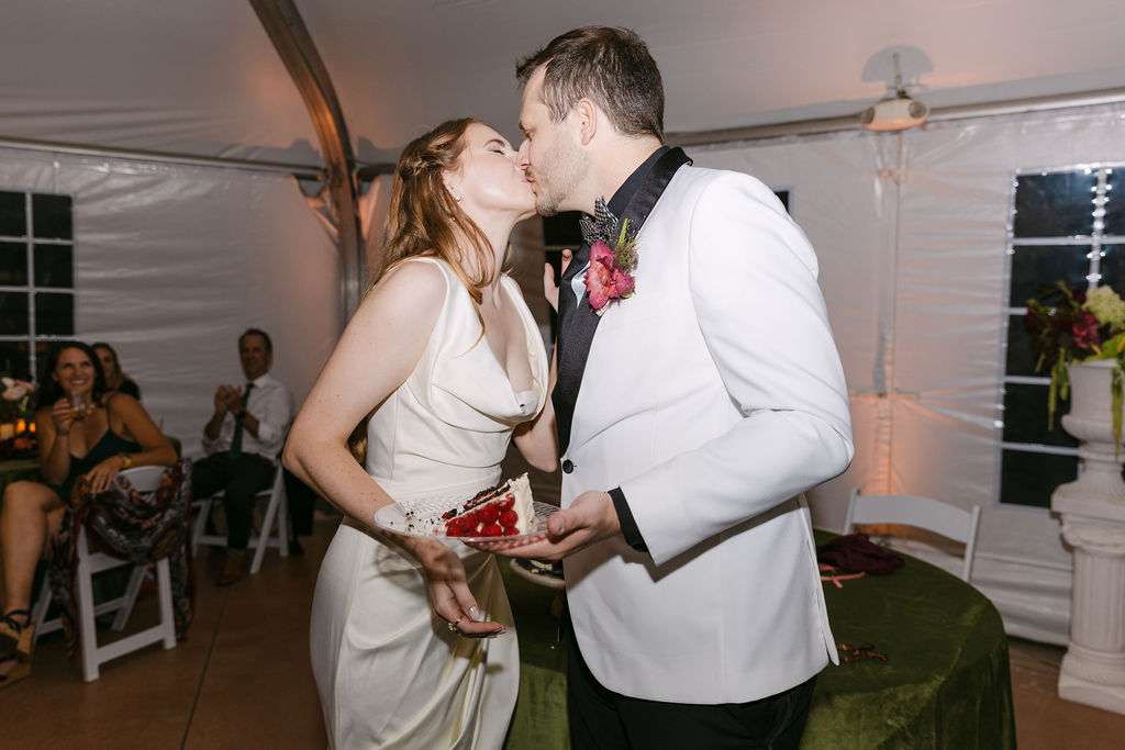 Bride and groom sharing a kiss beside their cake during an elegant Colorado wedding reception.