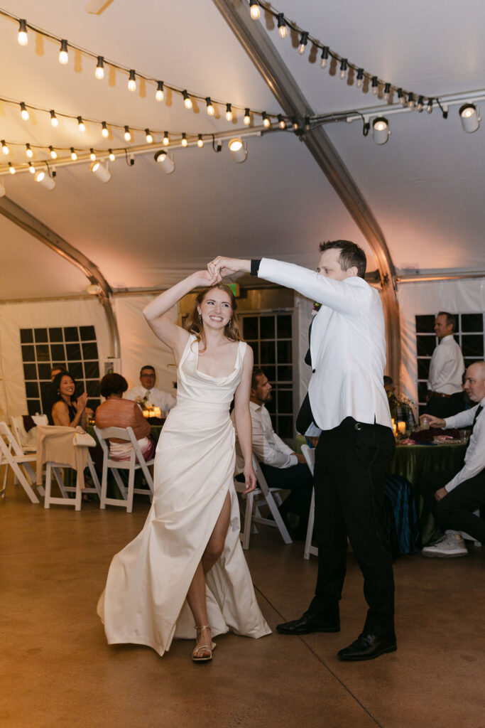Bride and groom spinning on the dance floor during their tented reception at Hudson Gardens.